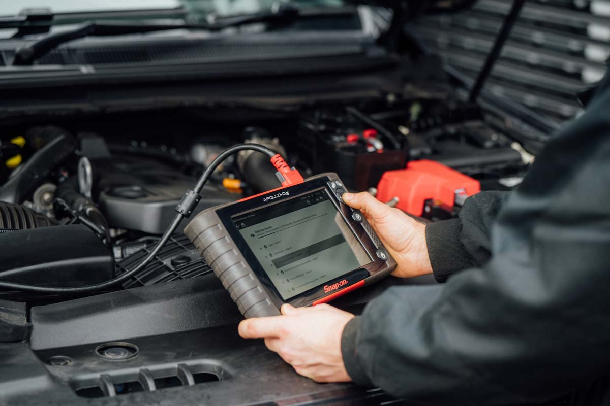 Technician running a scan tool on an engine bay